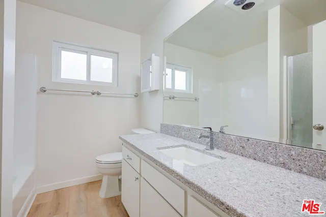 a bathroom with a granite countertop sink a toilet and a mirror