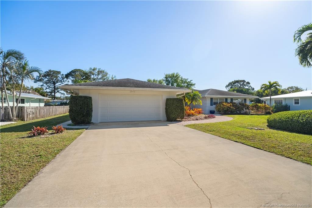 853 Northwest Spruce Ridge Drive Stuart, FL 34994 - Photo 2 of 20 a view of a white house with a yard and potted plants