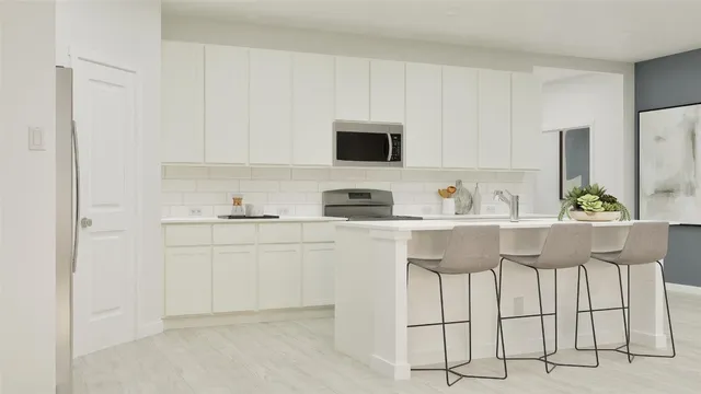 a kitchen with stainless steel appliances granite countertop white cabinets and a refrigerator