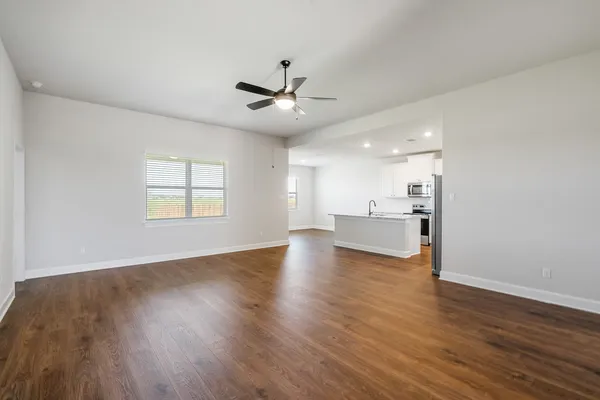 a kitchen with stainless steel appliances granite countertop a sink a stove a refrigerator and island with wooden floor