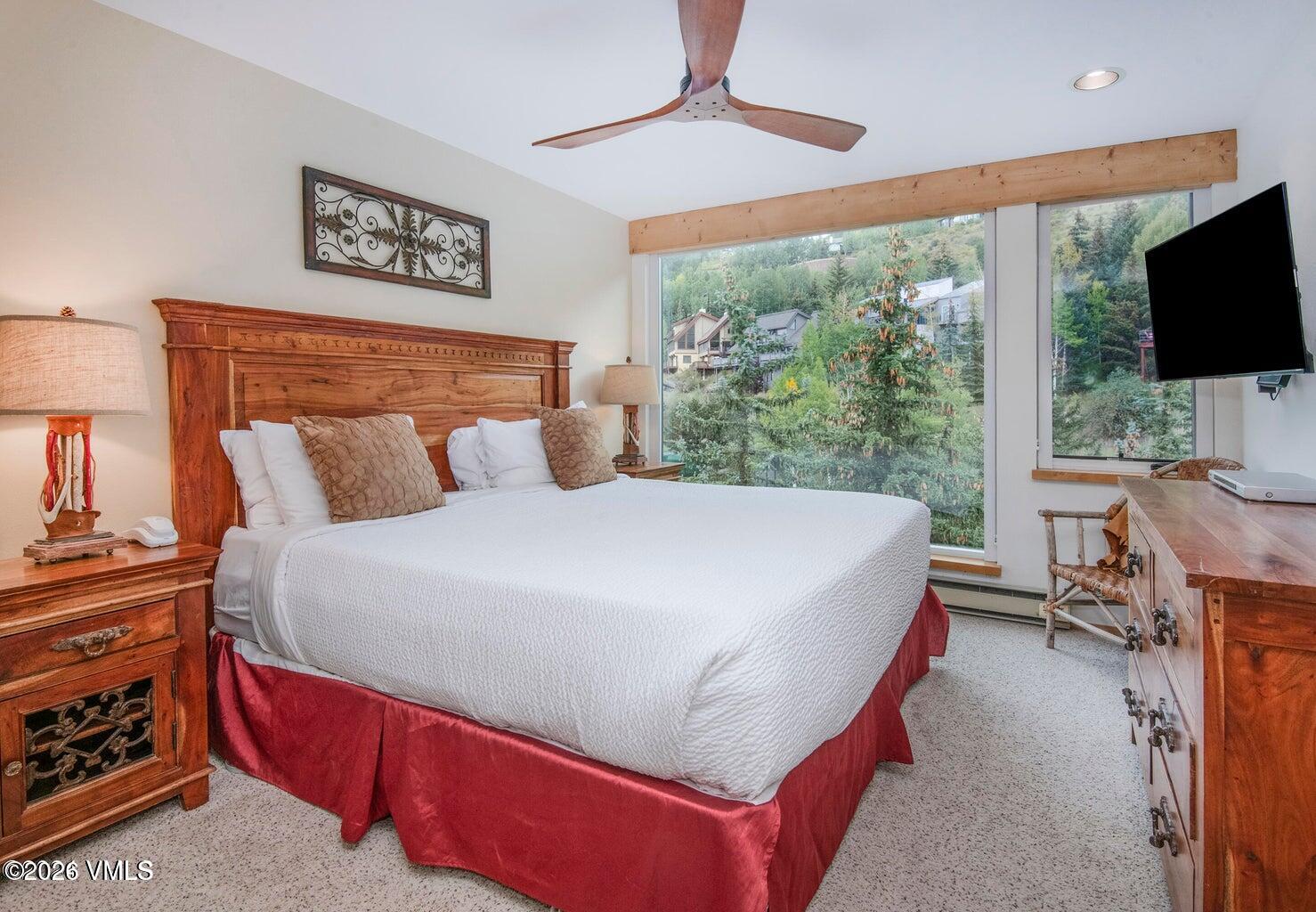 1100 North Frontage Road West, Unit 1519 Vail, CO 81657 - Photo 7 of 38 a bed sitting in a bedroom next to a window with a flat screen tv and a fireplace