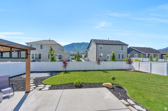252 North Sunrise Rnch Drive Mapleton, UT 84664 - Photo 7 of 62 Expansive backyard featuring a concrete patio, a pergola with built-in lighting, a manicured lawn, and decorative rock landscaping