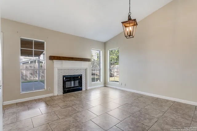 a view of an empty room with a fireplace and window