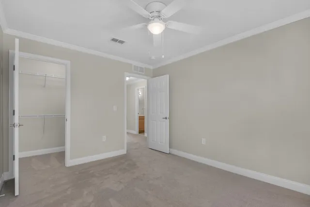 an empty room with closet and a ceiling fan