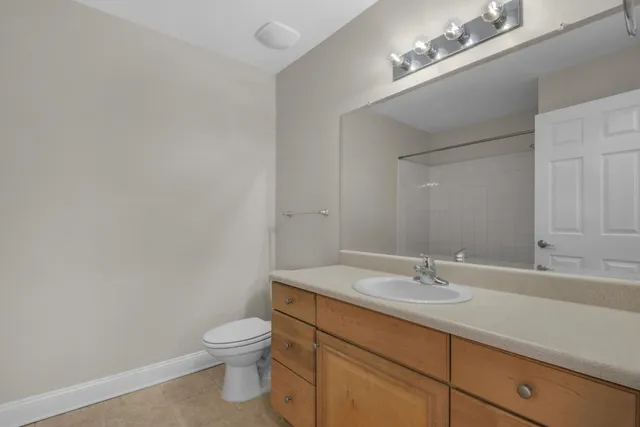 a bathroom with a granite countertop toilet a sink and a mirror