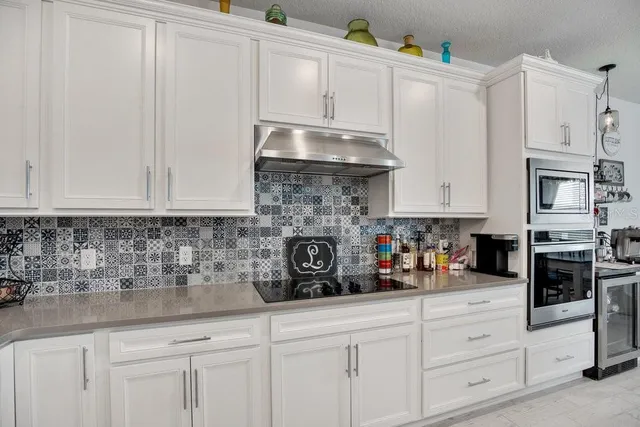 a kitchen with stainless steel appliances granite countertop white cabinets and a stove