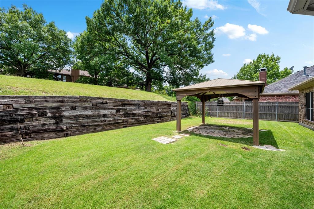 5607 Ranger Drive Rockwall, TX 75032 - Photo 37 of 40 Expansive green lawn with a wood-framed gazebo featuring a stone-paved patio