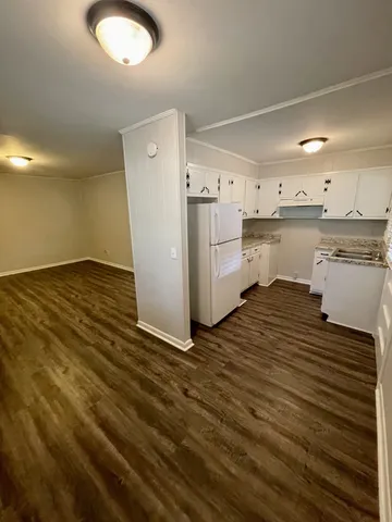 a view of a kitchen with white cabinets and wooden floor