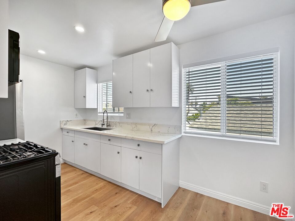2841 South Sycamore Avenue, Unit 3 Los Angeles, CA 90016 - Photo 7 of 16 a kitchen with granite countertop a stove a sink a cabinets and wooden floor