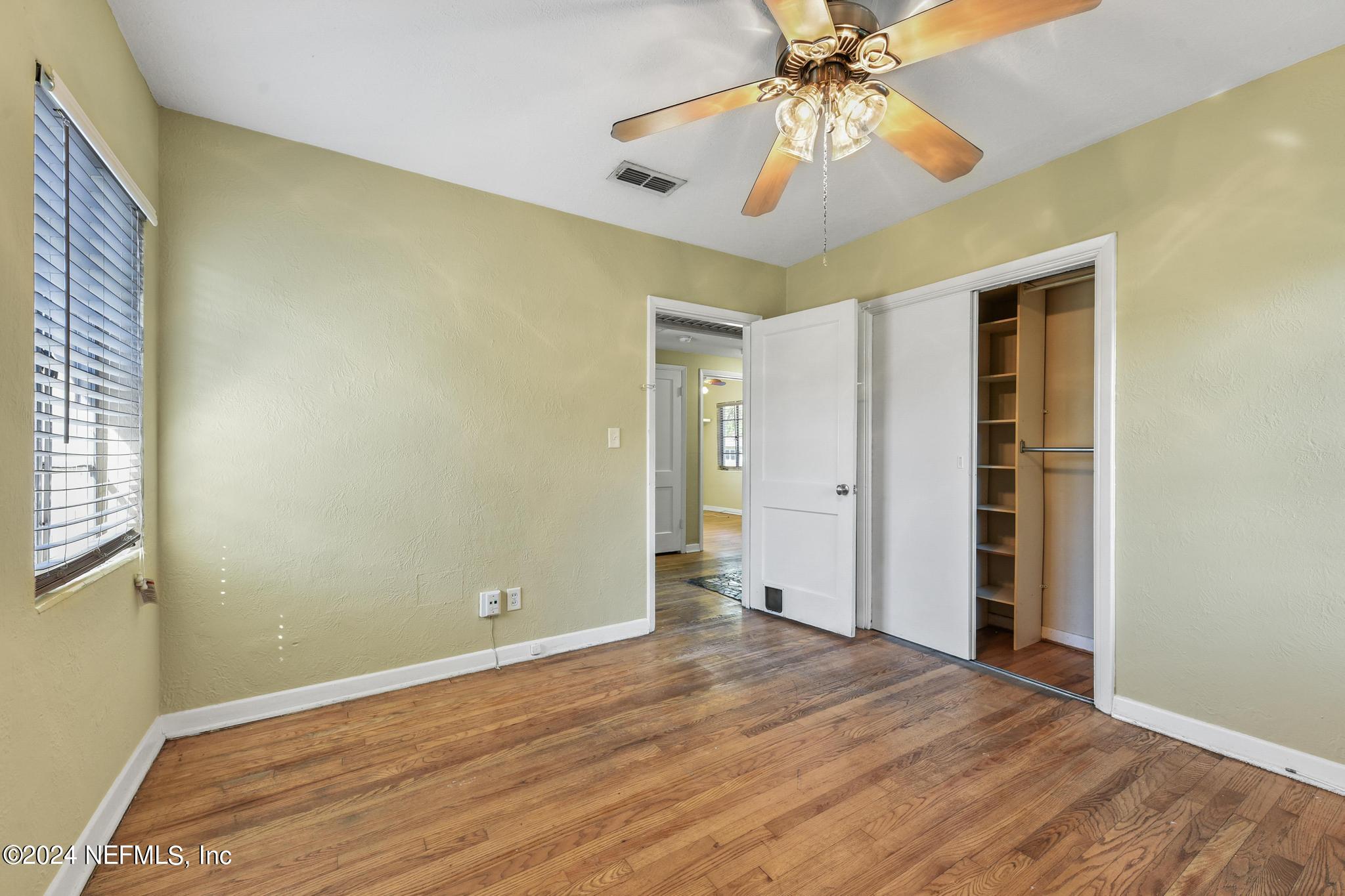 6029 Duke Road Jacksonville, FL 32217 - Photo 16 of 23 an empty room with a chandelier fan and wooden floor