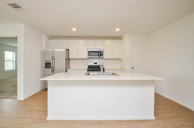 a view of kitchen with kitchen island a sink wooden floor and refrigerator