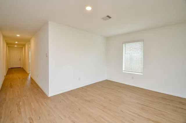 an empty room with wooden floor and windows