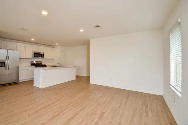 a view of kitchen with refrigerator and white cabinets