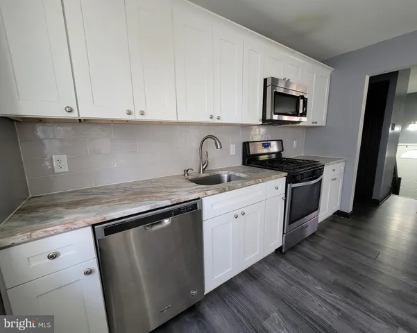 a kitchen with granite countertop white cabinets and black stainless steel appliances