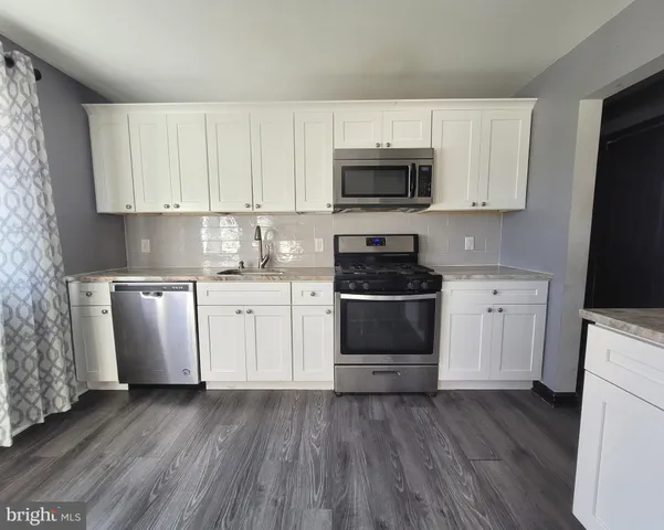 a kitchen with white cabinets stainless steel appliances and sink