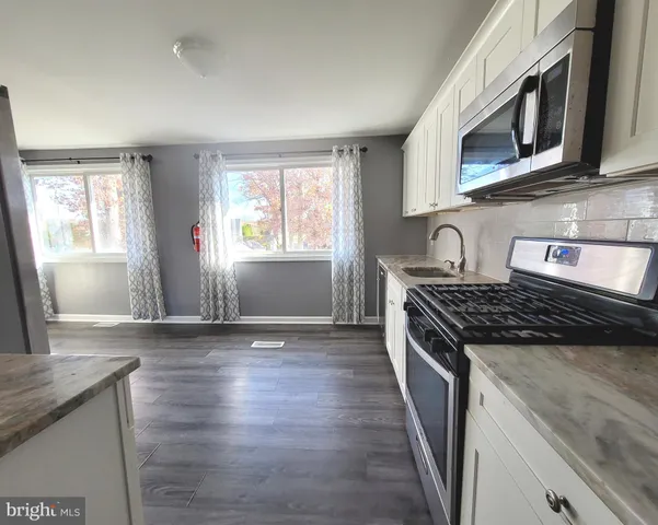 a kitchen with granite countertop wooden cabinets stove top oven and sink