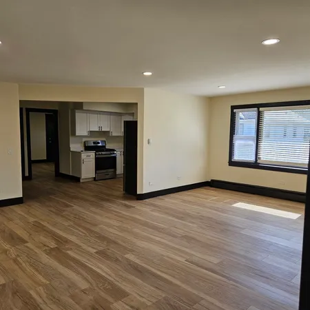 a view of an empty room with a kitchen and wooden floor