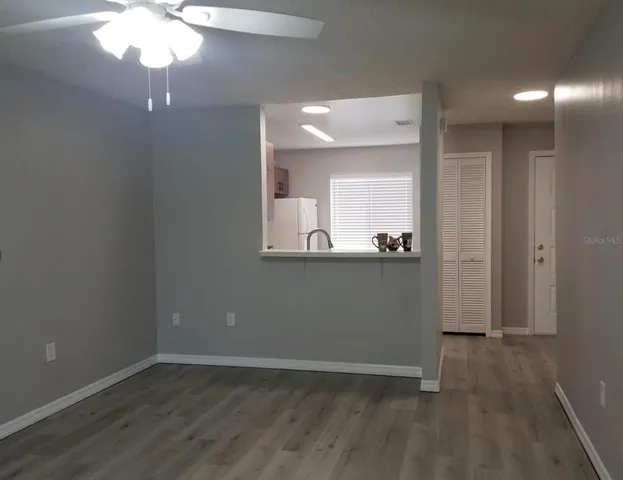 an empty room with wooden floor fan and windows