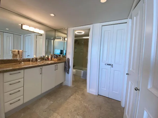 a spacious bathroom with a double vanity sink a large mirror and a shower