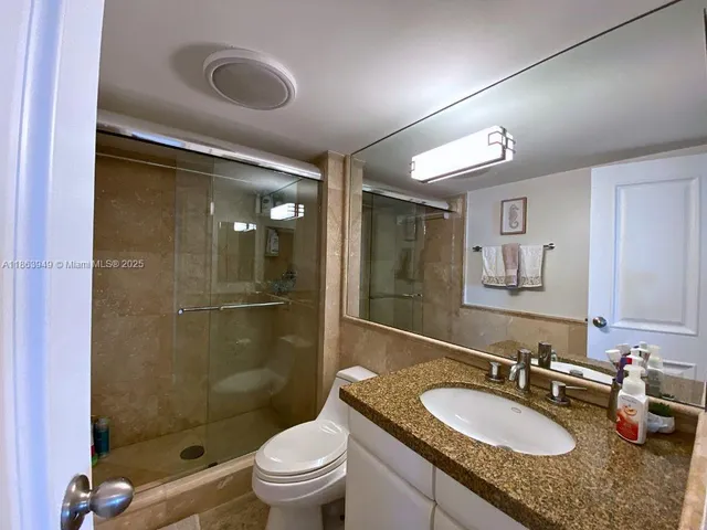 a bathroom with a granite countertop sink mirror toilet and shower