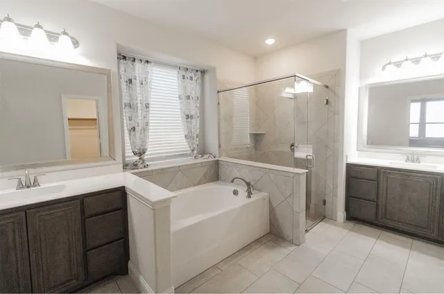 a spacious bathroom with a tub sink shower and mirror
