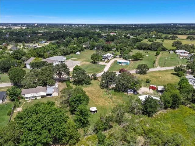 an aerial view of residential houses with outdoor space and trees