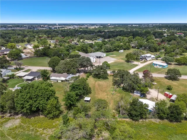 an aerial view of residential houses with outdoor space and trees