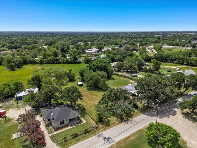 an aerial view of residential houses with outdoor space and trees