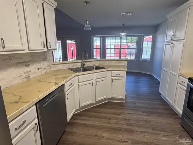 a kitchen with stainless steel appliances granite countertop a sink cabinets and wooden floor