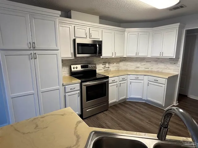 a kitchen with white cabinets and white appliances