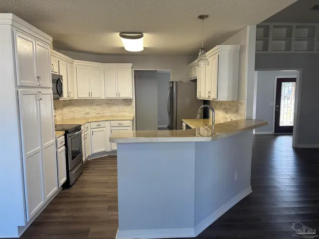 a kitchen with stainless steel appliances granite countertop a refrigerator a sink dishwasher and white cabinets with wooden floor