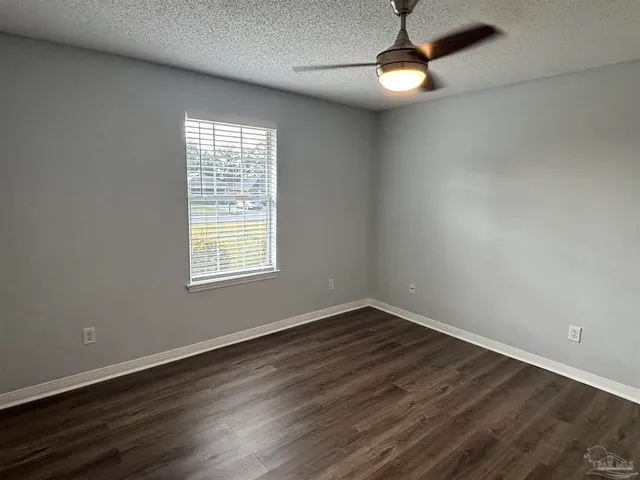 a view of an empty room with wooden floor exposed radiator and a window