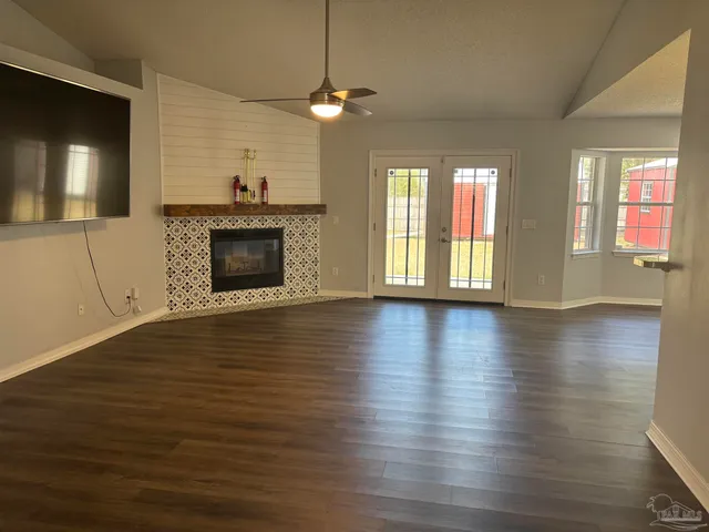 an empty room with wooden floor fireplace and windows