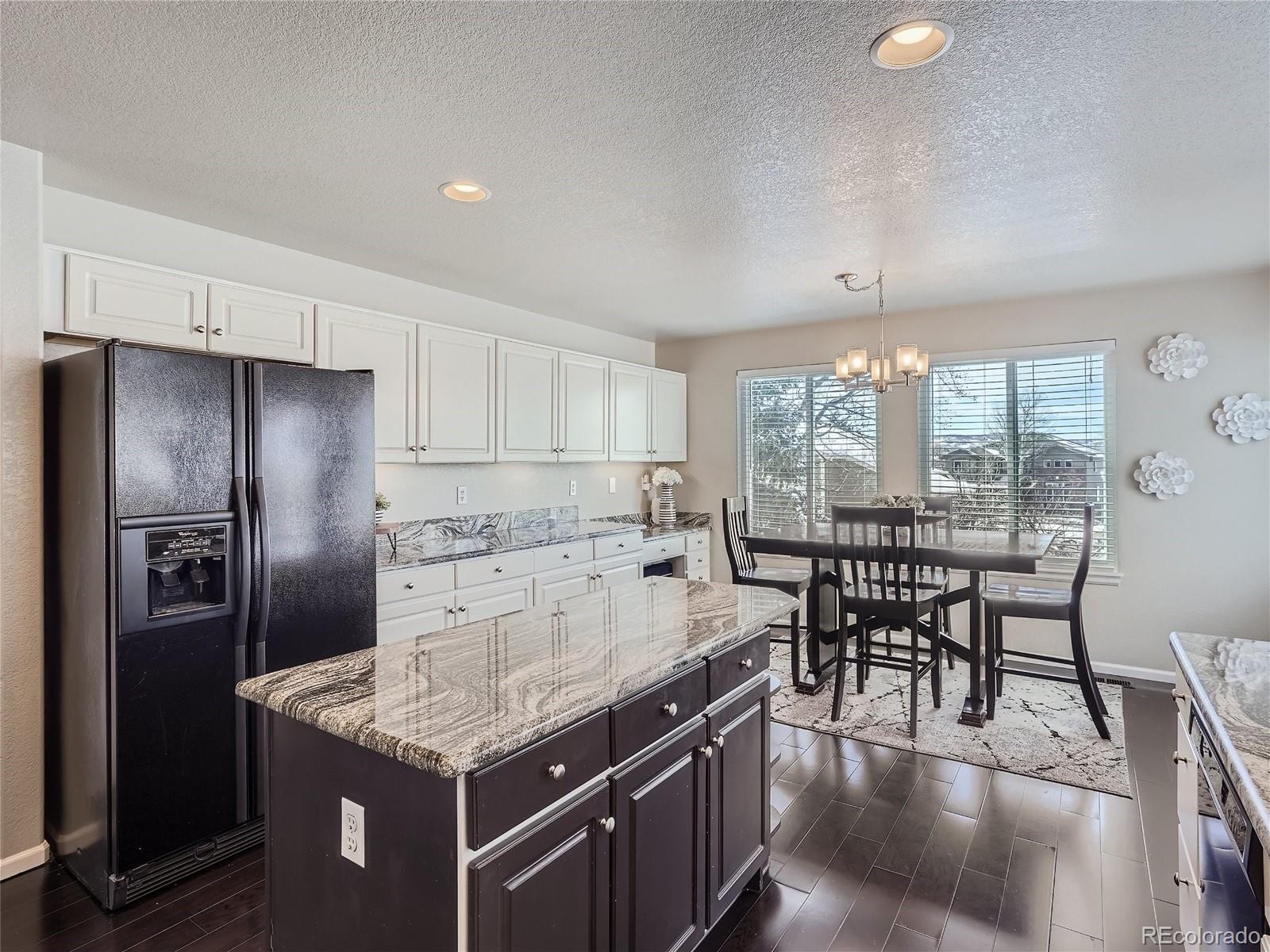6596 Millstone Street Highlands Ranch, CO 80130 - Photo 11 of 33 a kitchen with stainless steel appliances granite countertop a table chairs and a refrigerator