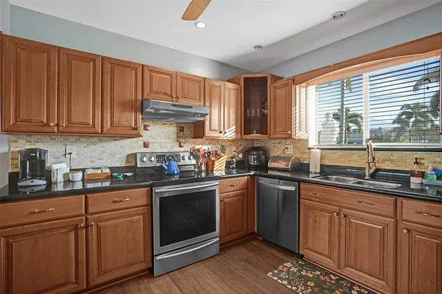 a kitchen with granite countertop cabinets stainless steel appliances a sink and window