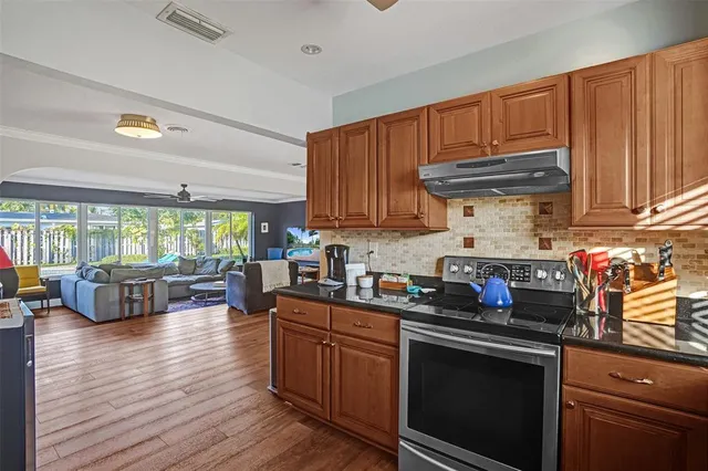 a kitchen with granite countertop a stove a sink dishwasher and cabinets with wooden floor