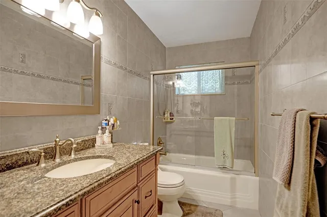 a bathroom with a granite countertop sink toilet and shower