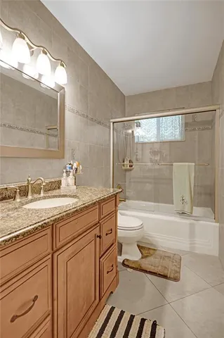 a bathroom with a granite countertop sink toilet mirror and bathtub