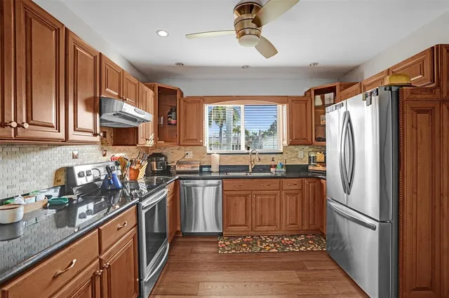 a kitchen with stainless steel appliances granite countertop a refrigerator a sink dishwasher a stove top oven a refrigerator and cabinets