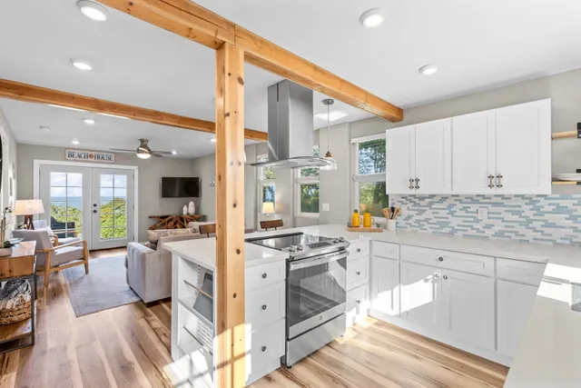 a kitchen with stainless steel appliances granite countertop a stove a sink and white cabinets with wooden floor