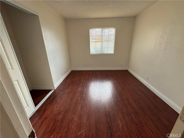 an empty room with wooden floor and window