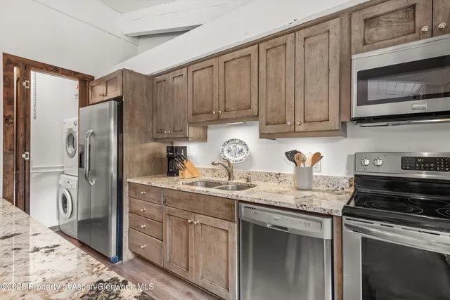 a kitchen with stainless steel appliances granite countertop a refrigerator sink and stove