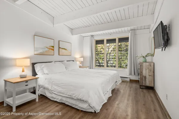 a bedroom with a large bed and a flat tv screen