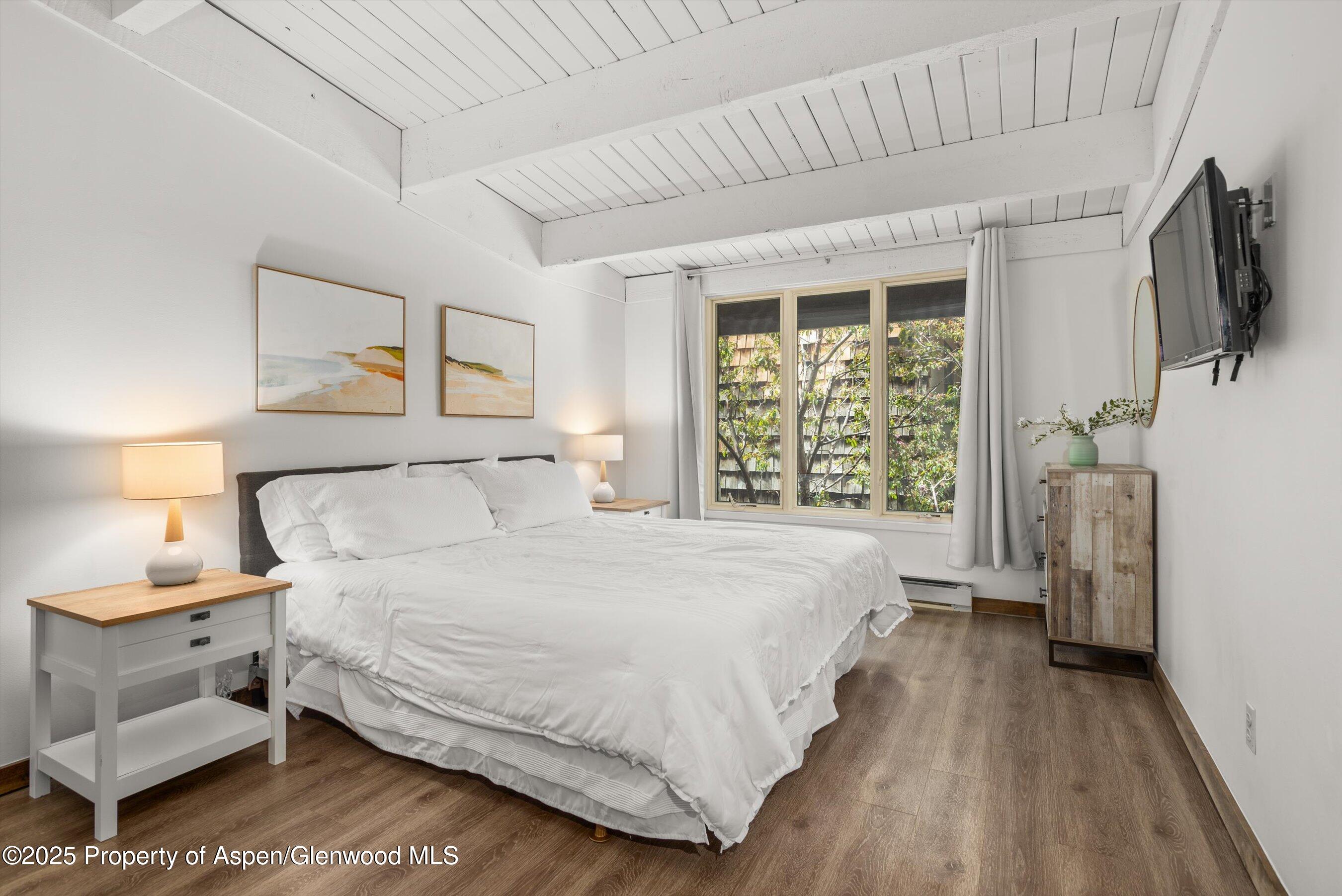 1039 East Cooper Avenue, Unit 36B Aspen, CO 81611 - Photo 10 of 15 a bedroom with a large bed and a flat tv screen