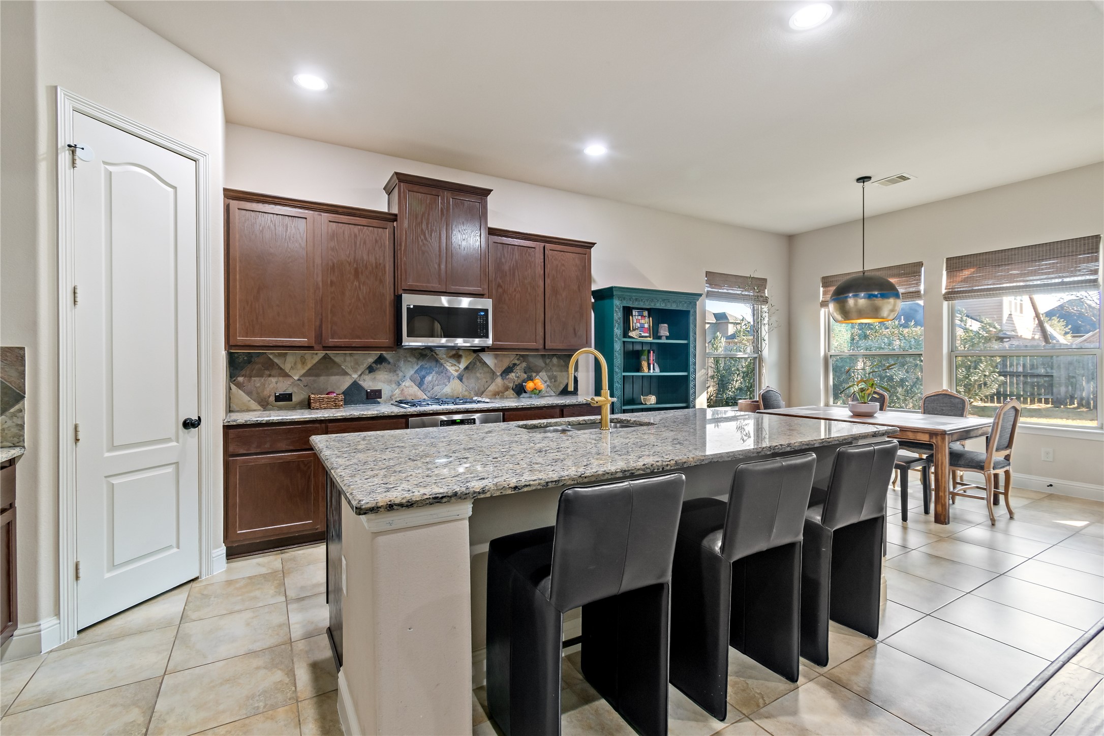 8126 Spreadwing Street Conroe, TX 77385 - Photo 15 of 30 This kitchen features a spacious open design with modern cabinets, granite countertops, and an island with seating. It has ample natural light and a dining area, creating a welcoming space for cooking and entertaining. Walk in pantry for storage