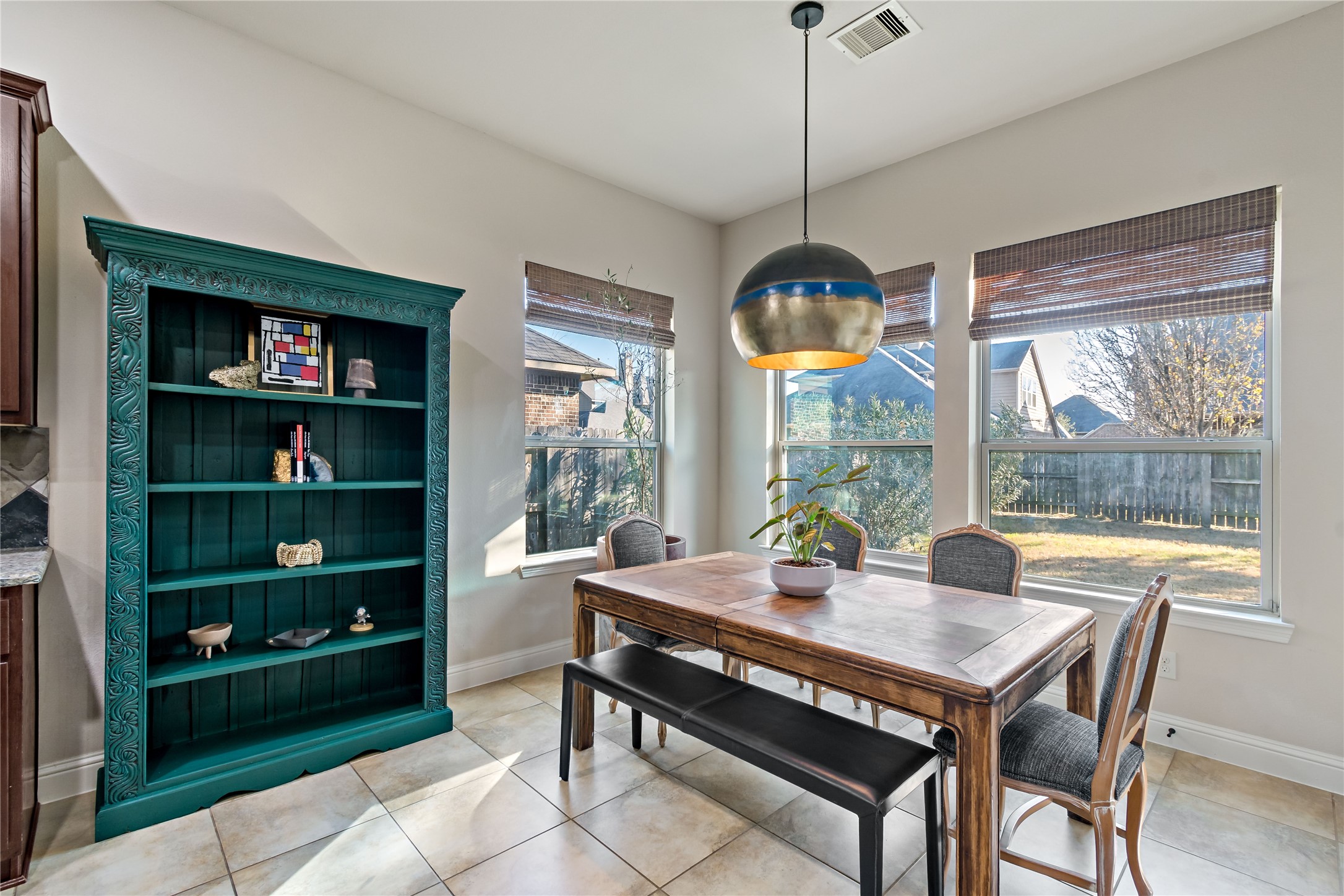 8126 Spreadwing Street Conroe, TX 77385 - Photo 16 of 30 Bright dining area featuring large windows, a modern light fixture, and a cozy table setup. There's a stylish teal bookshelf adding character to the space. Ideal for casual dining with a view of the backyard.