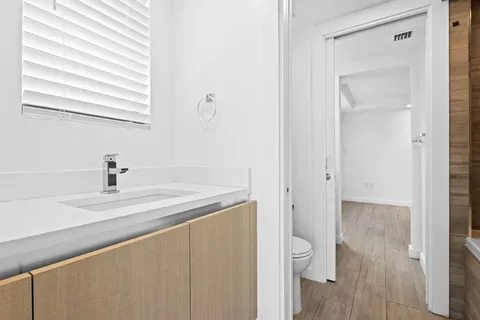 a bathroom with a granite countertop sink a toilet and a window