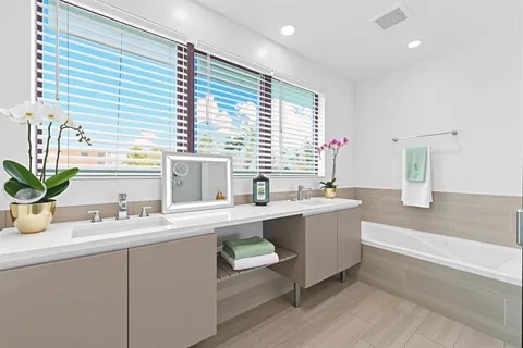 a bathroom with a tub a sink and a large mirror