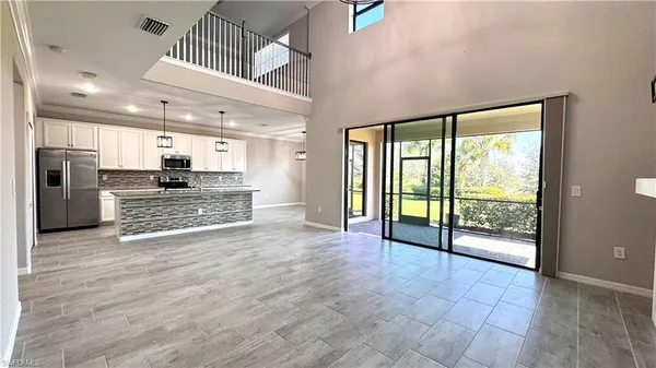 a view of an empty room with kitchen and a window
