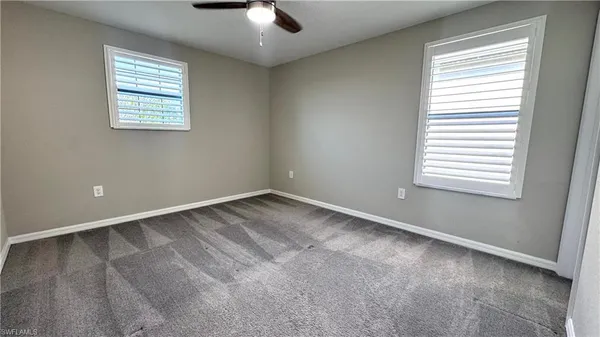 an empty room with a window and a fan